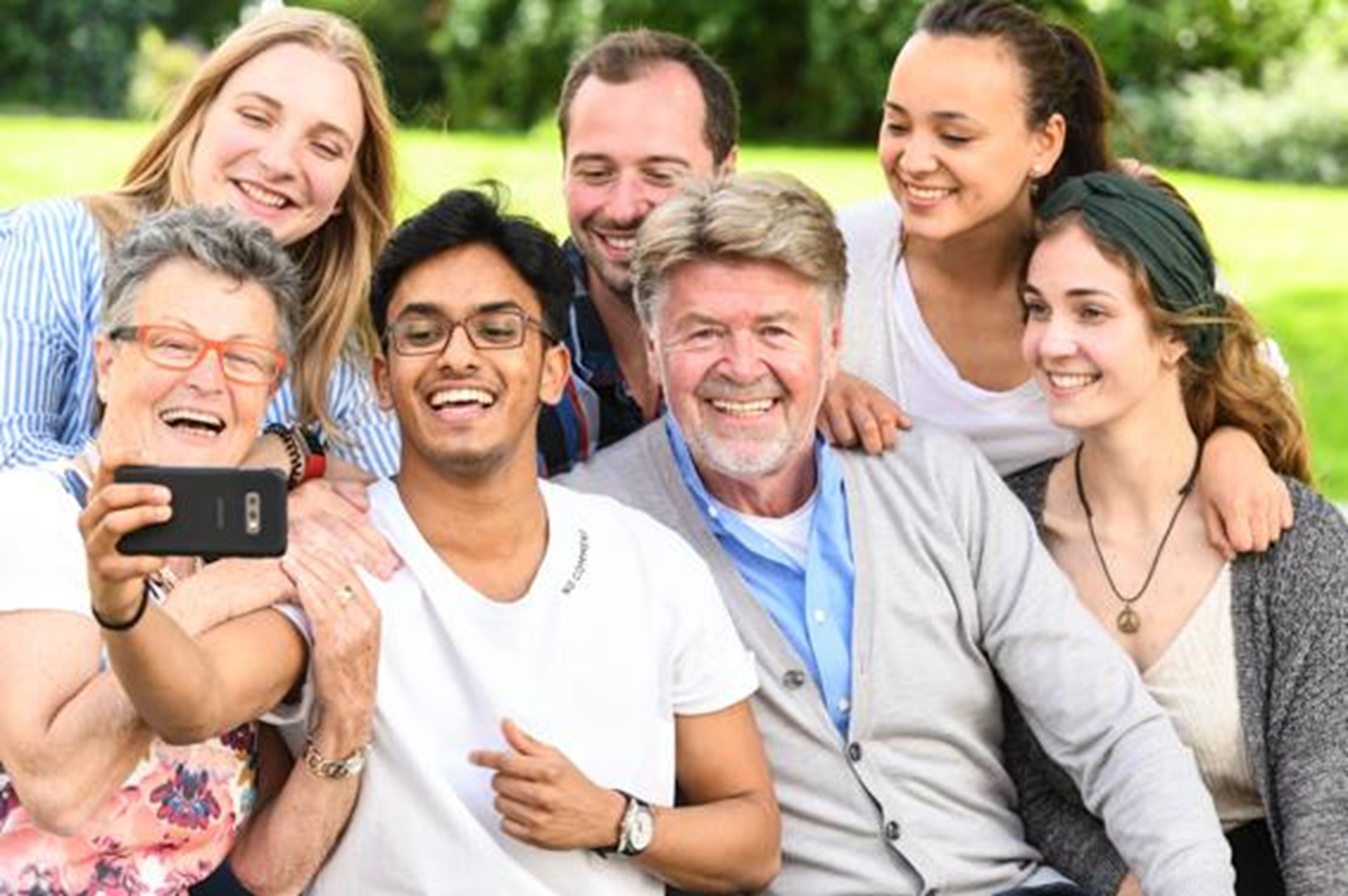 junge freiwillig Engagierte fotografieren sich zusammen mit älteren Menschen mit dem Smartphone