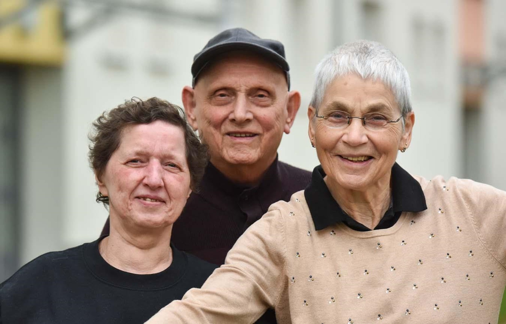 Zwei ältere Frauen und ein älterer Mann blicken in die Kamera