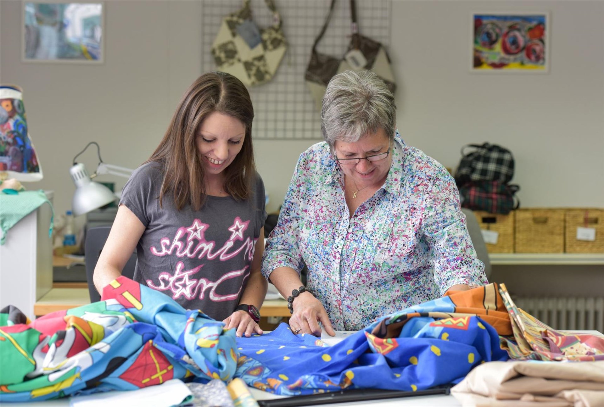 zwei Frauen schauen in der Nähstube Stoff an