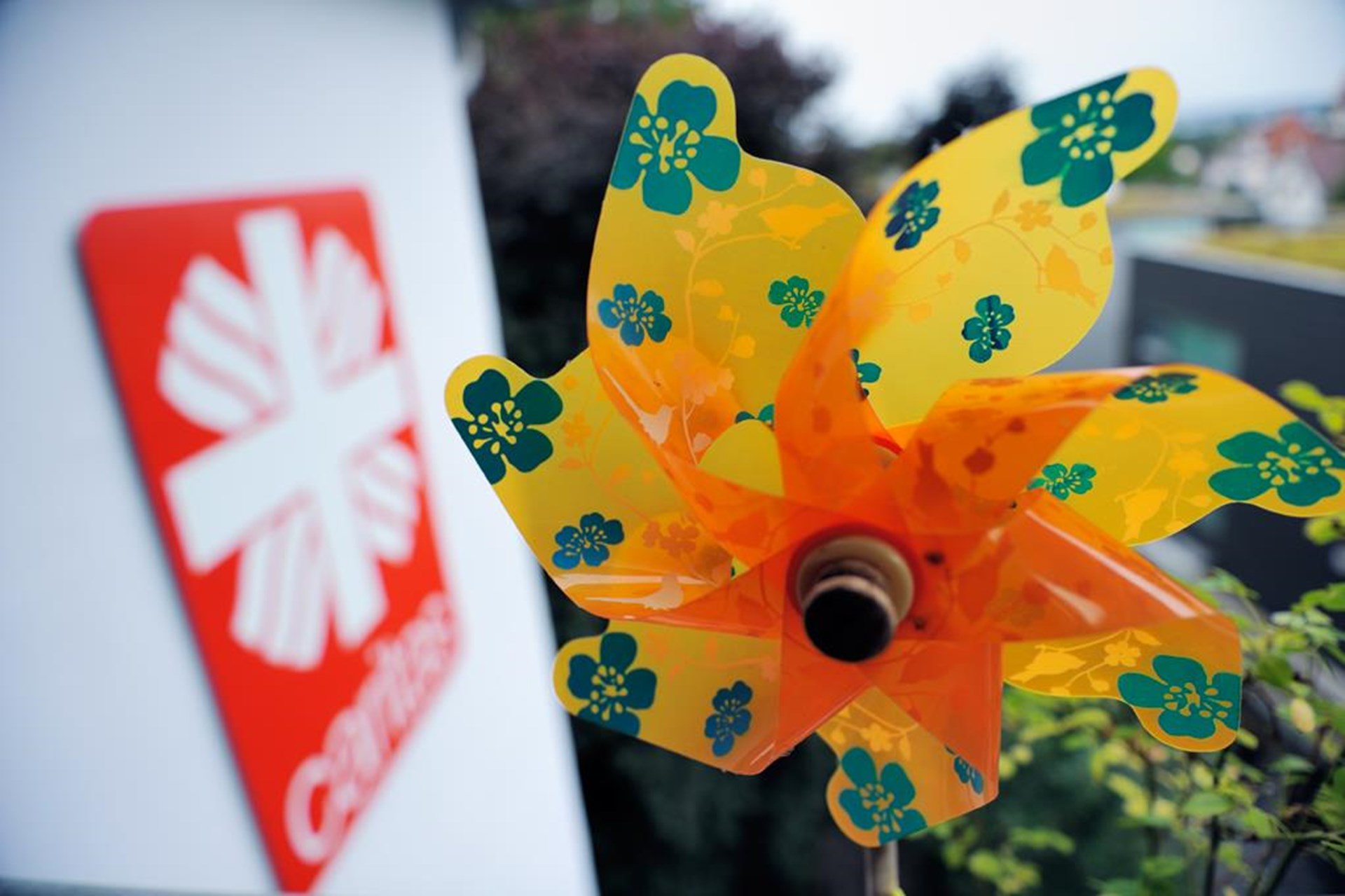 buntes Windrad mit Caritaslogo im Hintergrund